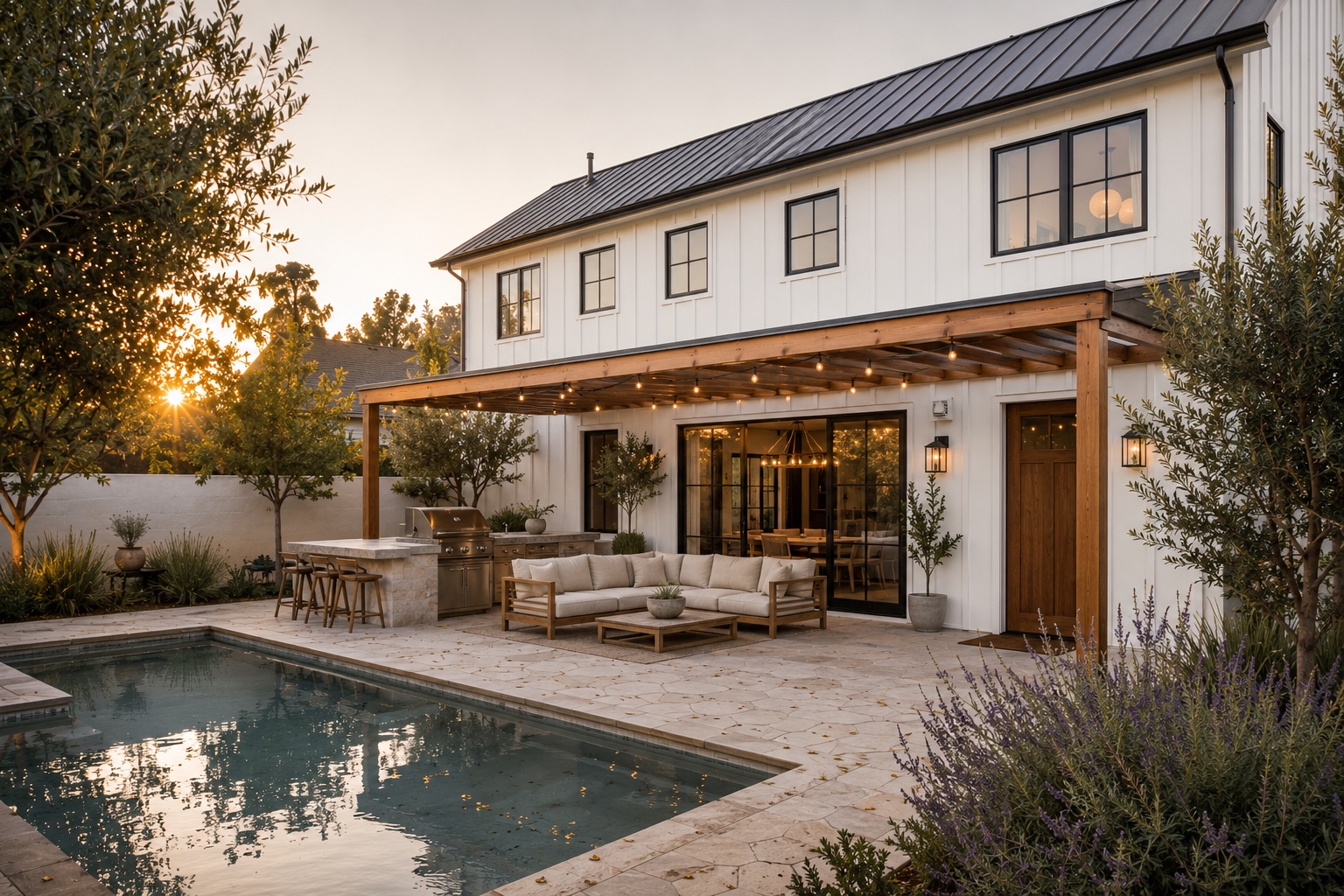 Custom home backyard with pool and outdoor living at sunset by Estate Design & Construction